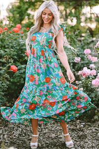 Robe longue verte à fleurs multicolores, bretelles volantées, jupe ample avec volants.