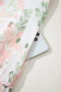 Robe courte rose à fleurs, bas volanté et motif feuillagé vert.