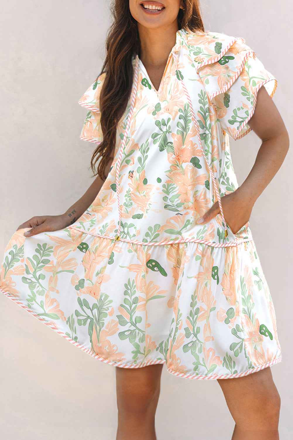 Robe courte blanche à motifs végétaux orange et verts, manches volantées, col V.