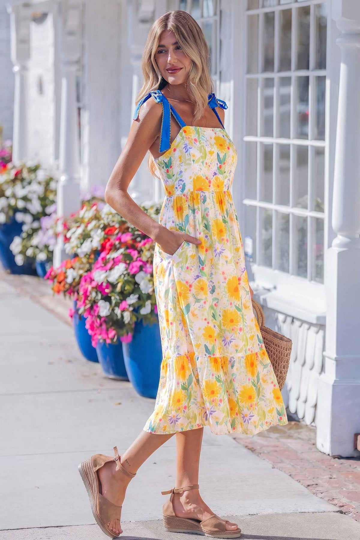 Robe midi imprimé floral jaune, bretelles avec nœuds bleus, volant évasé en bas.