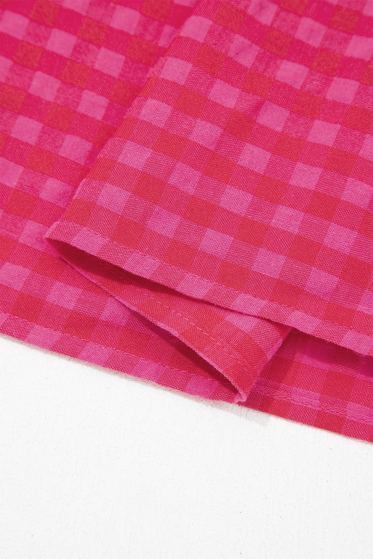 Ourlet froncé en tissu rouge à carreaux, avec bord replié et couture visible