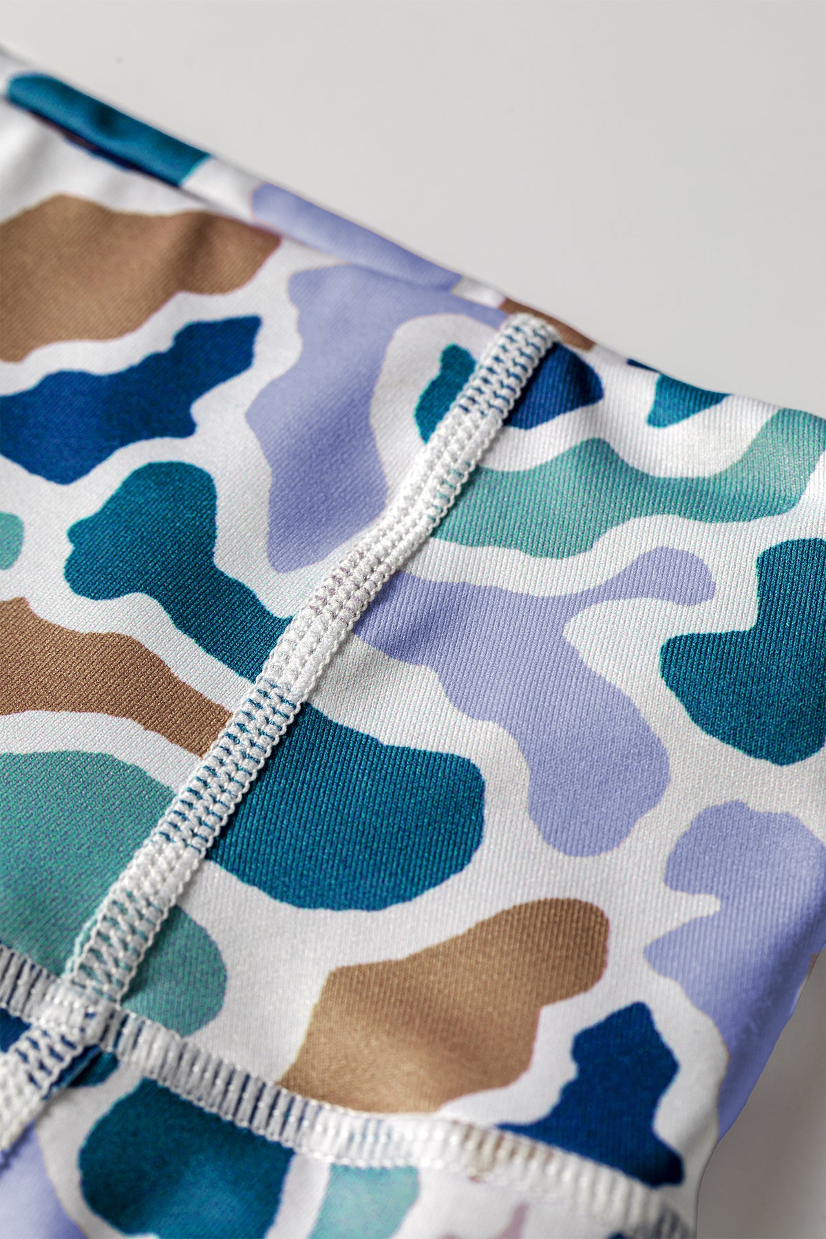 Bord de short cycliste en maille imprimée camouflage bleu, couture élastique visible.