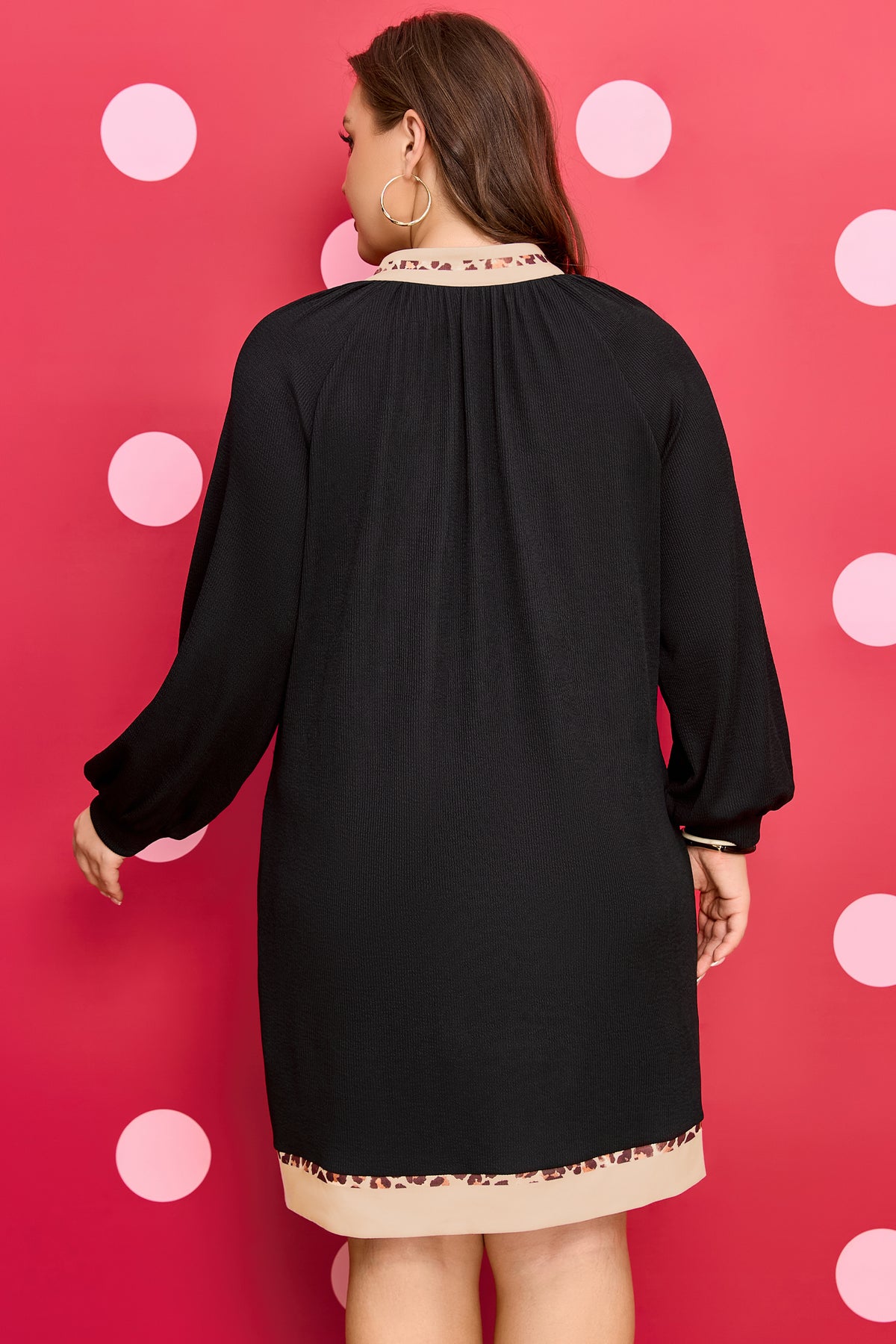 Robe mini noire vue de dos, ourlet bordé de léopard, manches longues bouffantes.