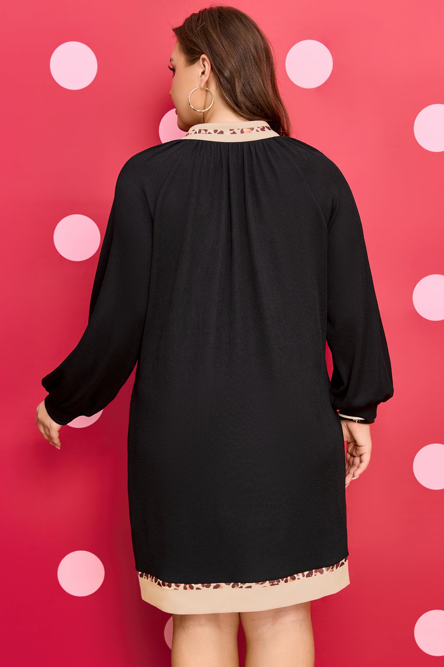 Robe mini noire vue de dos, ourlet bordé de léopard, manches longues bouffantes.