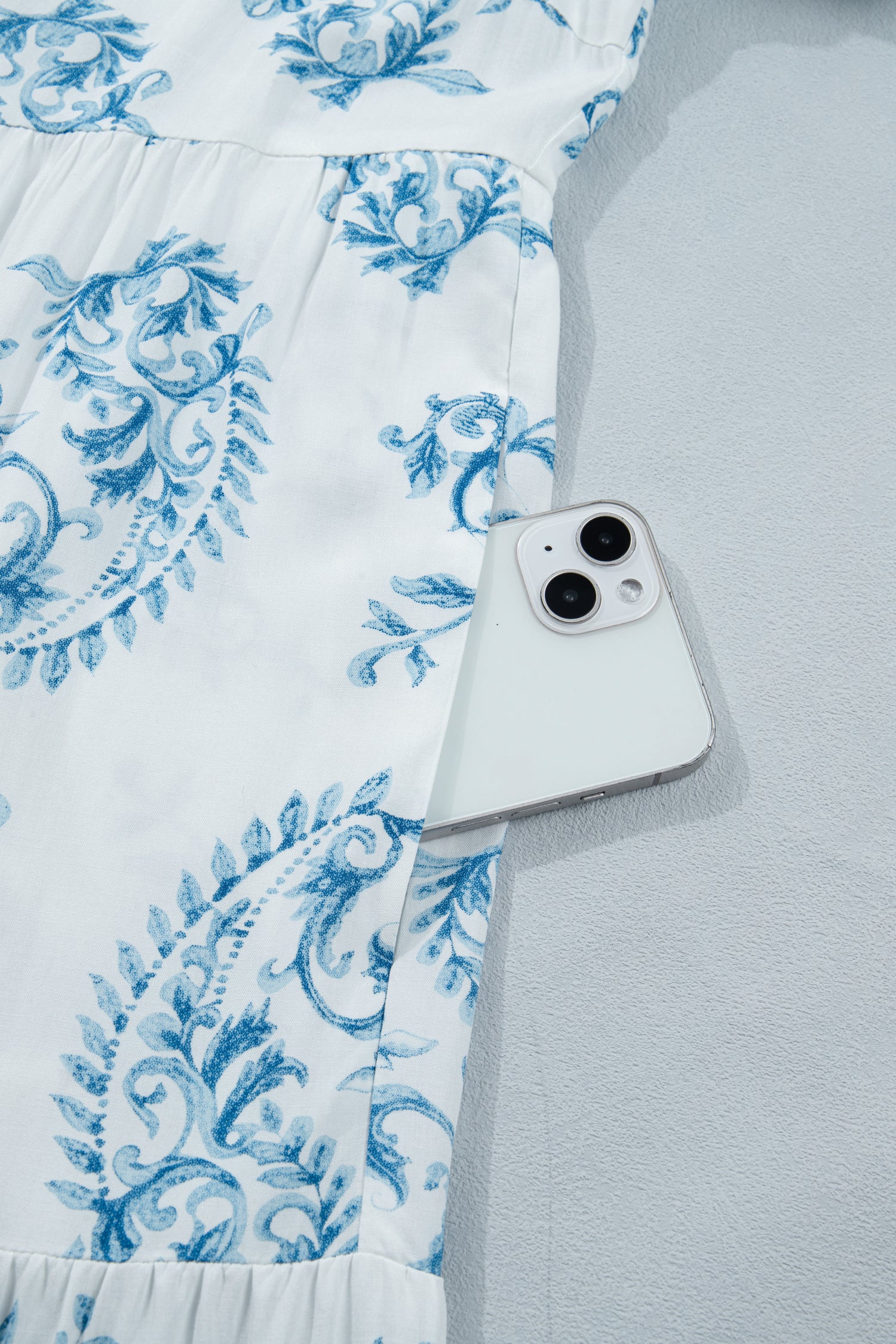 Tissu de robe bleu ciel à motifs floraux, détails de fronces et petites fleurs bleues.
