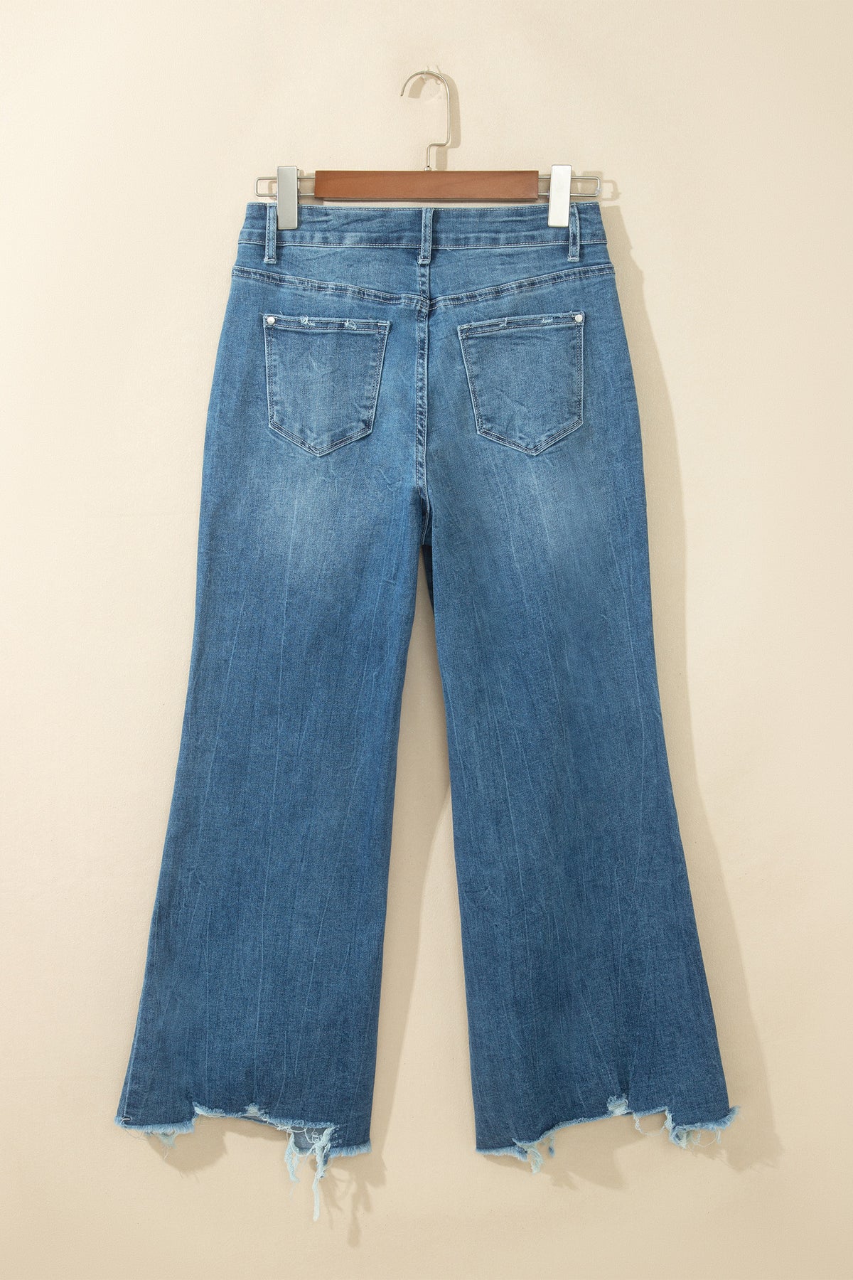 Jean flare taille haute bleu moyen, poches dos, ourlet effiloché avec bords usés.