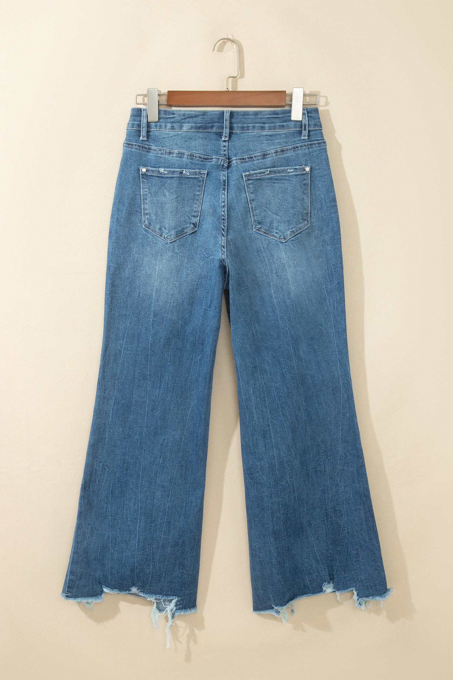 Jean flare taille haute bleu moyen, poches dos, ourlet effiloché avec bords usés.