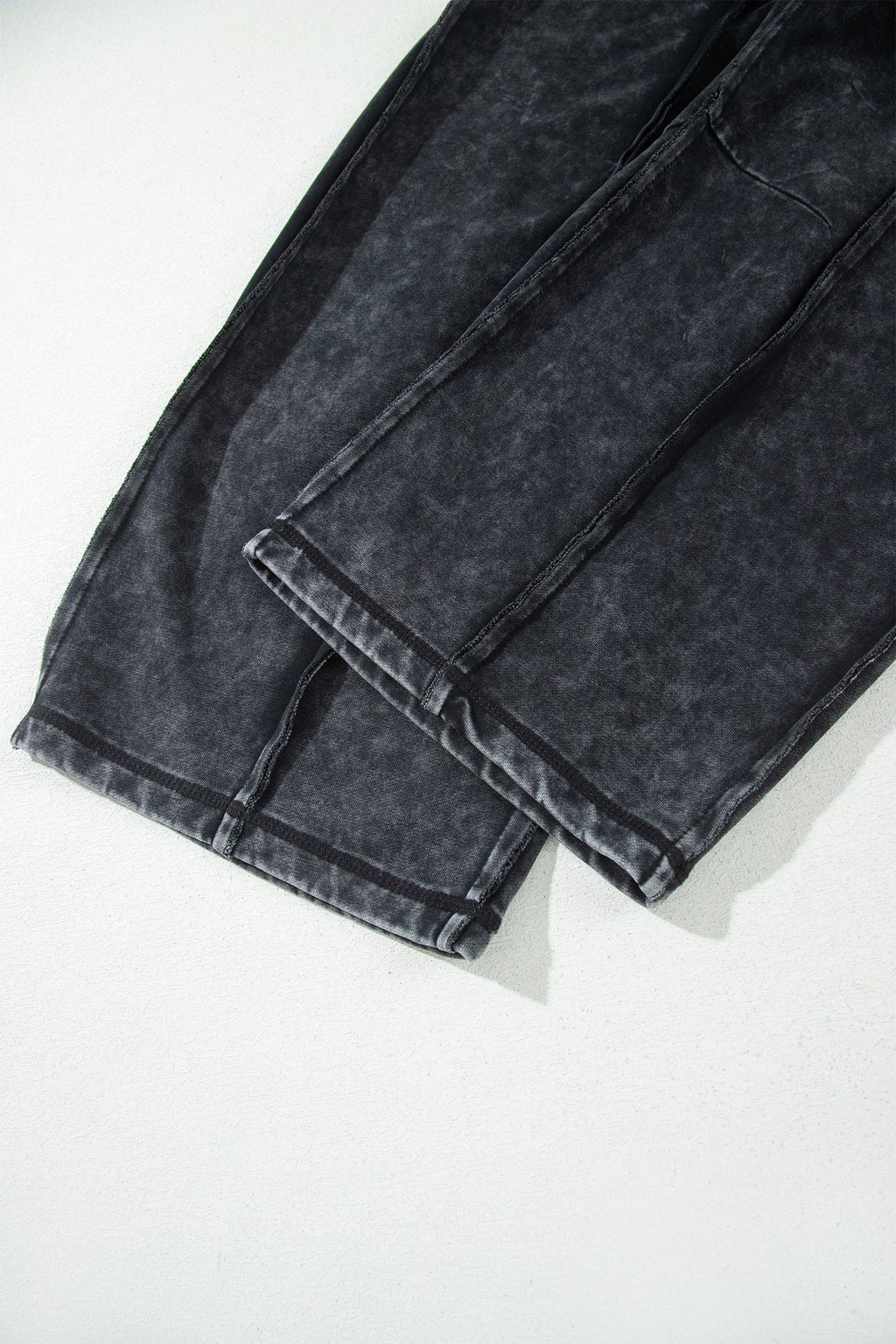 Bas de pantalon noir délavé minéral avec couture brute et ourlet retroussé, jambes larges