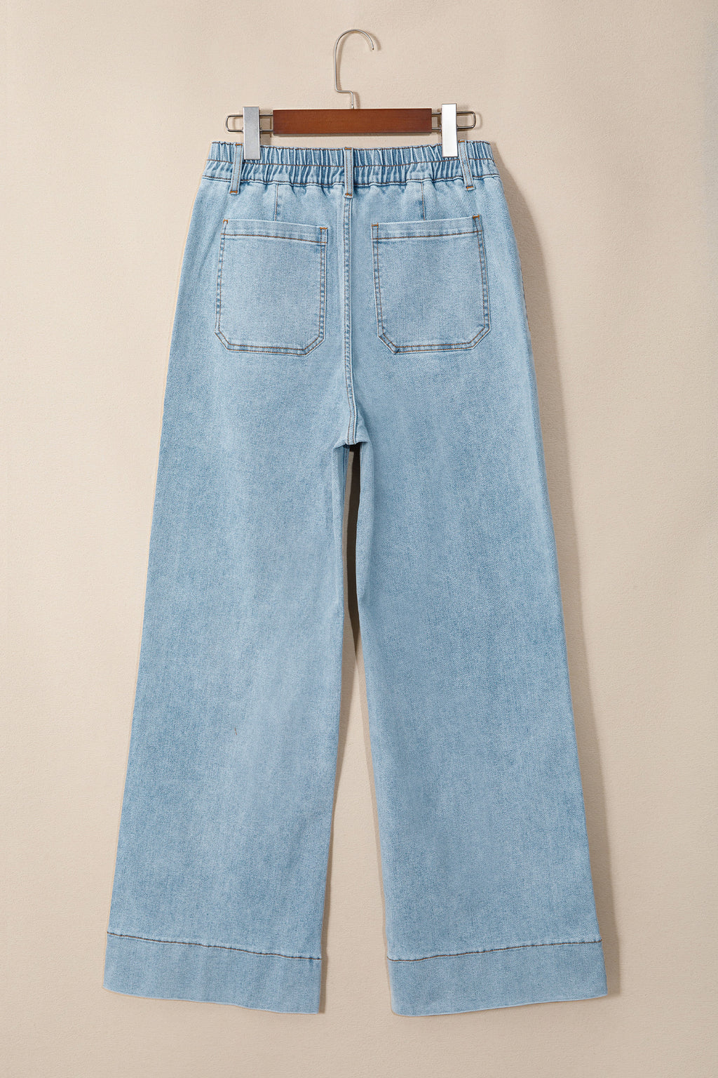 Jean en denim bleu ciel, taille élastiquée, jambe ample, poches avant visibles.