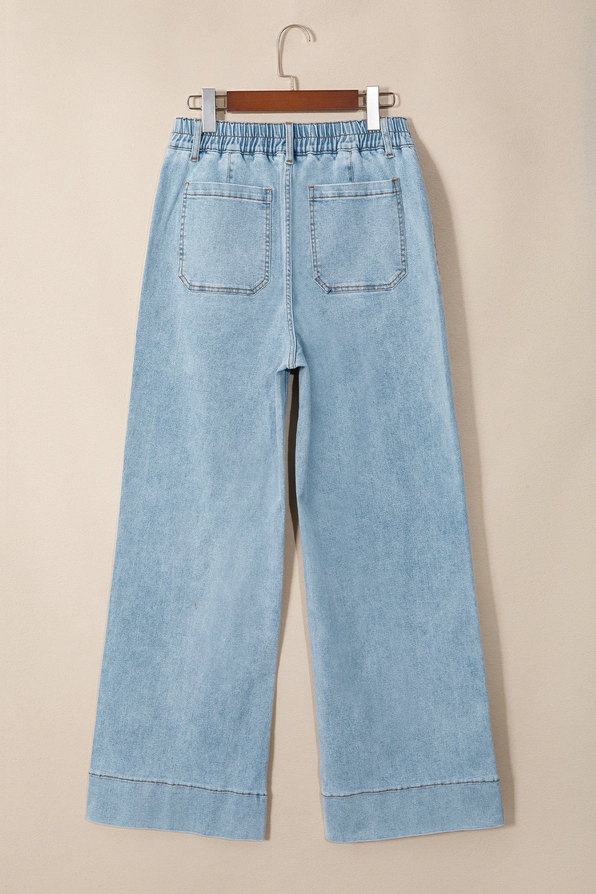 Jean en denim bleu ciel, taille élastiquée, jambe ample, poches avant visibles.