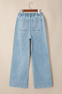 Jean en denim bleu ciel, taille élastiquée, jambe ample, poches avant visibles.