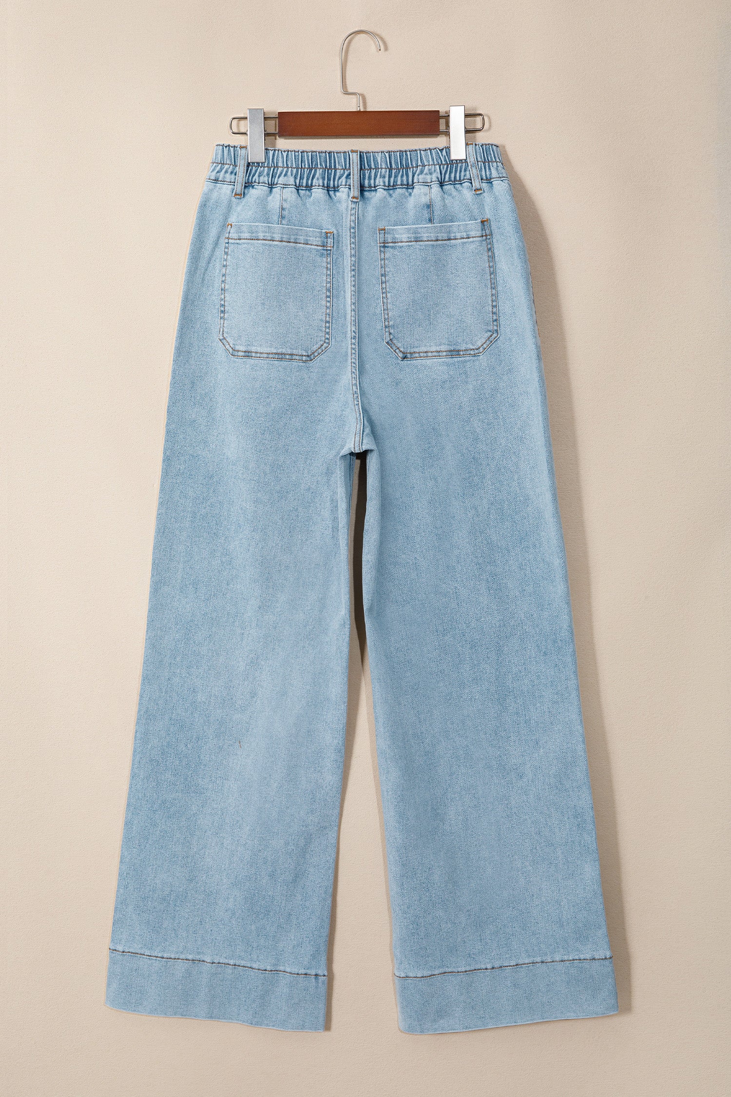 Jean en denim bleu ciel, taille élastiquée, jambe ample, poches avant visibles.