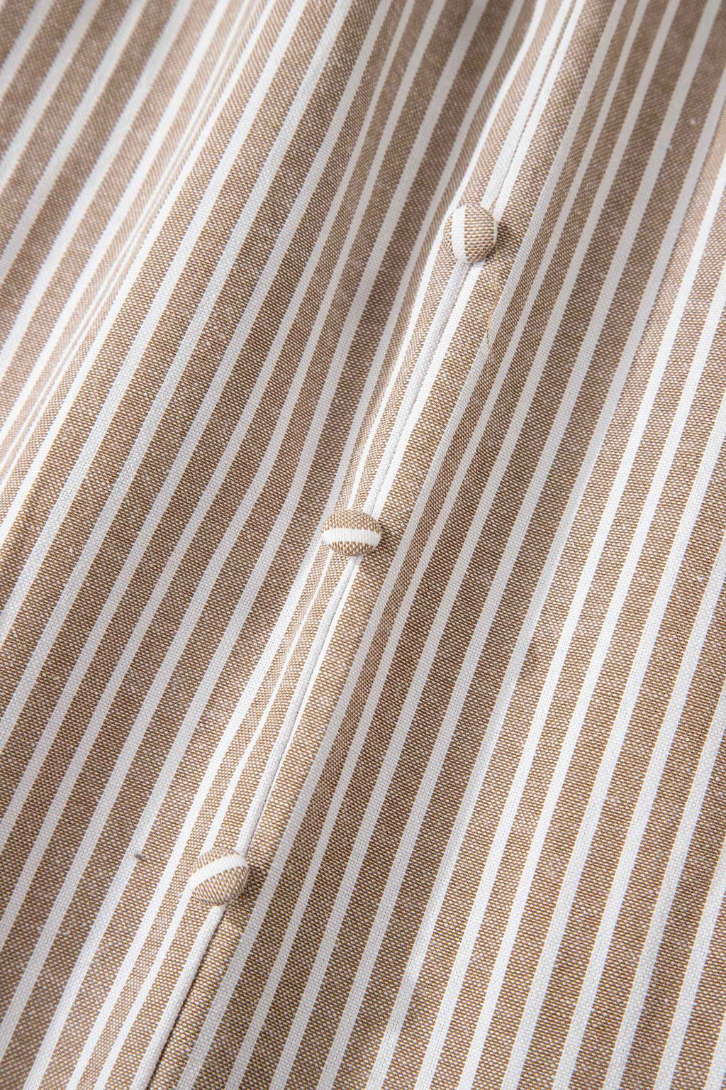 Détail de robe rayée : tissu texturé et boutons alignés au centre.