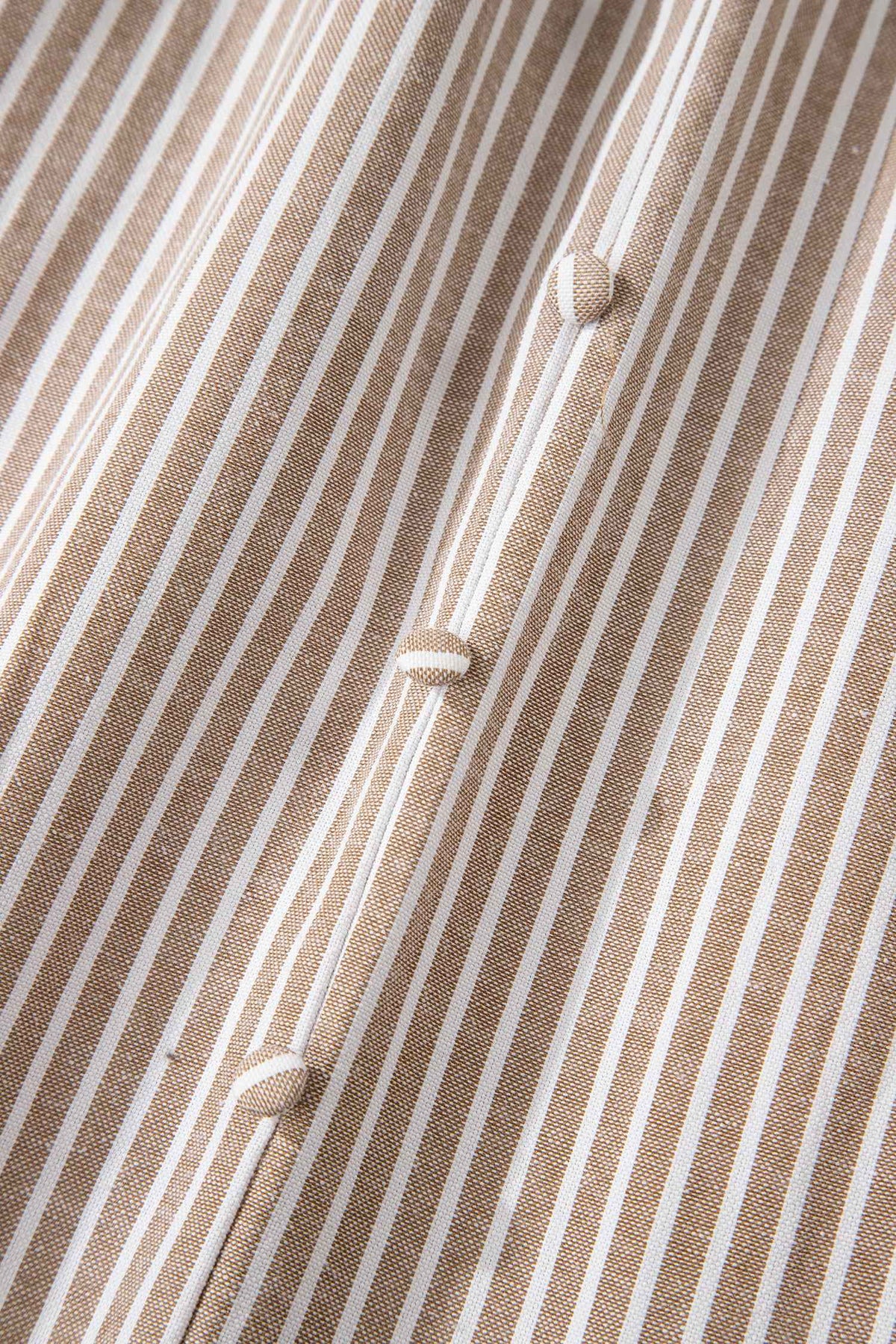 Détail de robe rayée : tissu texturé et boutons alignés au centre.