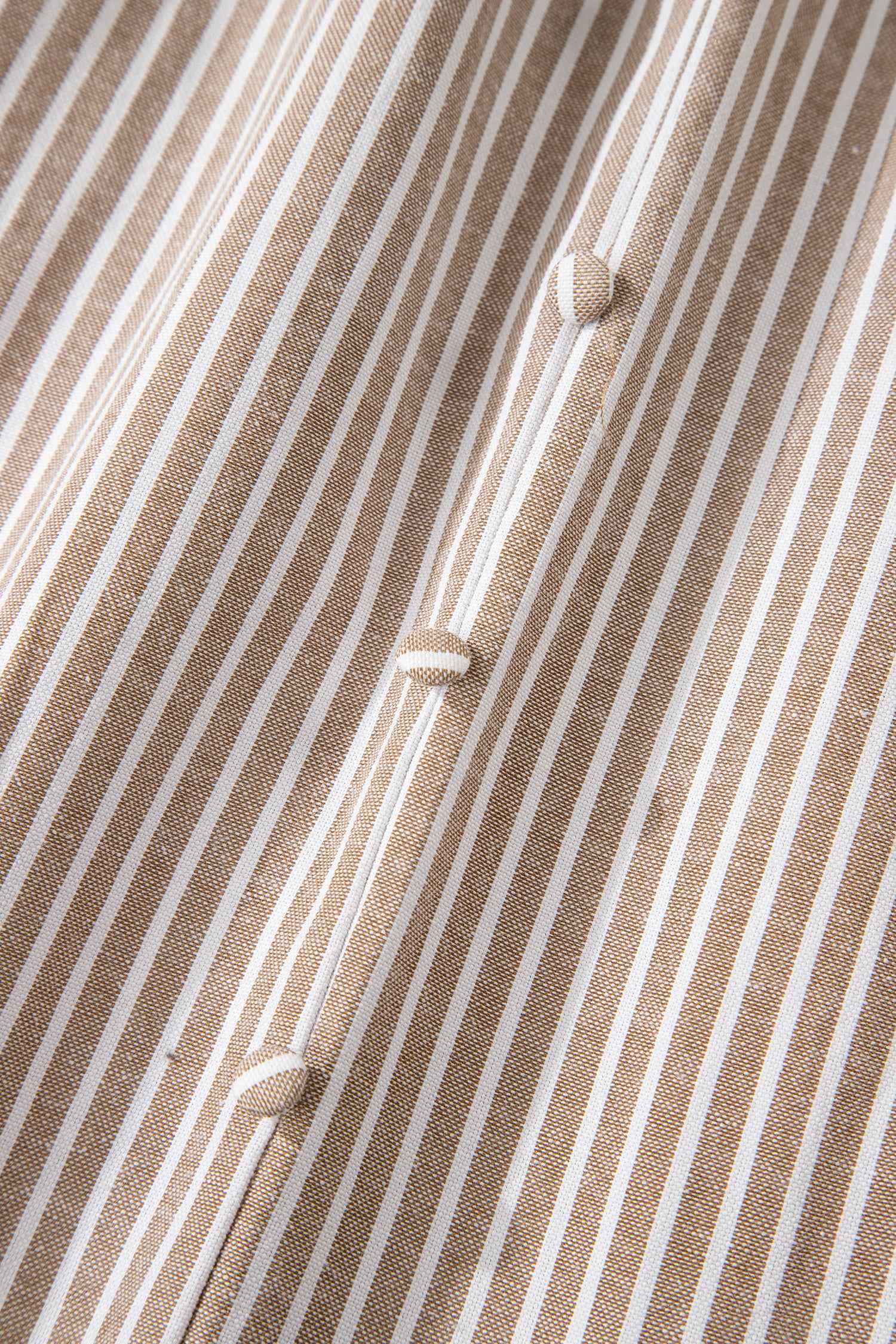 Détail de robe rayée : tissu texturé et boutons alignés au centre.