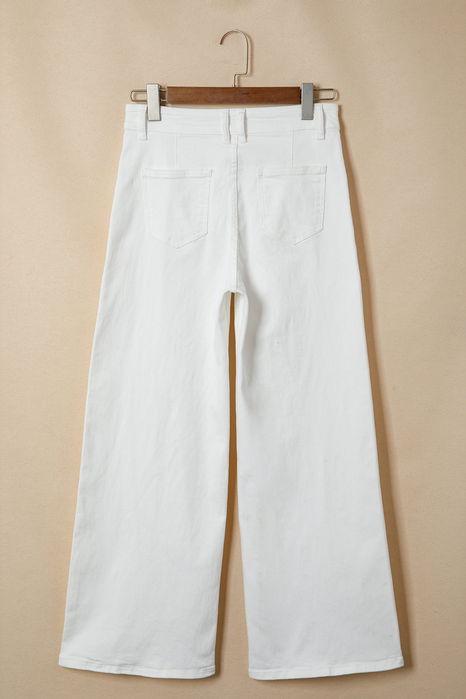 Jean blanc femme sur cintre, taille mi-haute, jambes évasées, poches arrières et braguette.