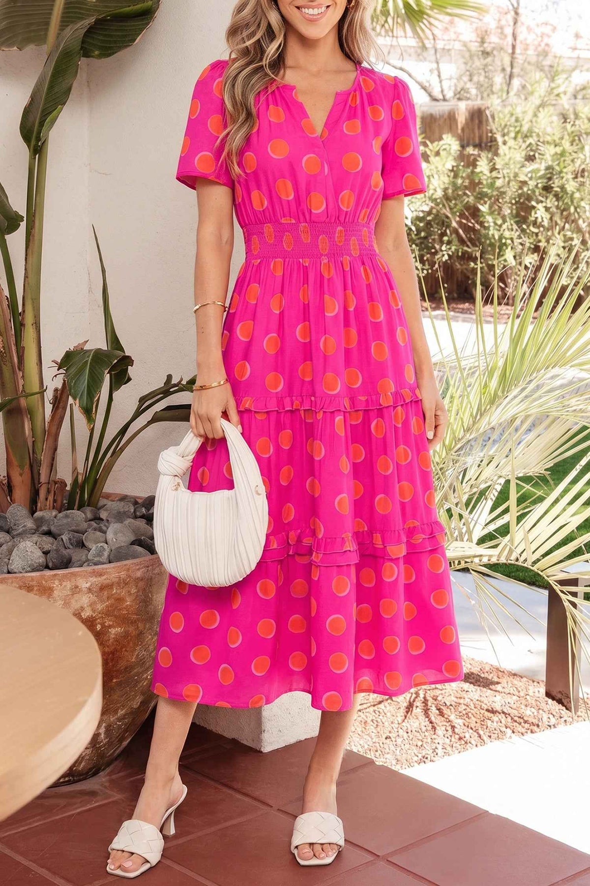 Robe mi-longue rose à pois jaune, encolure V, volants étagés.