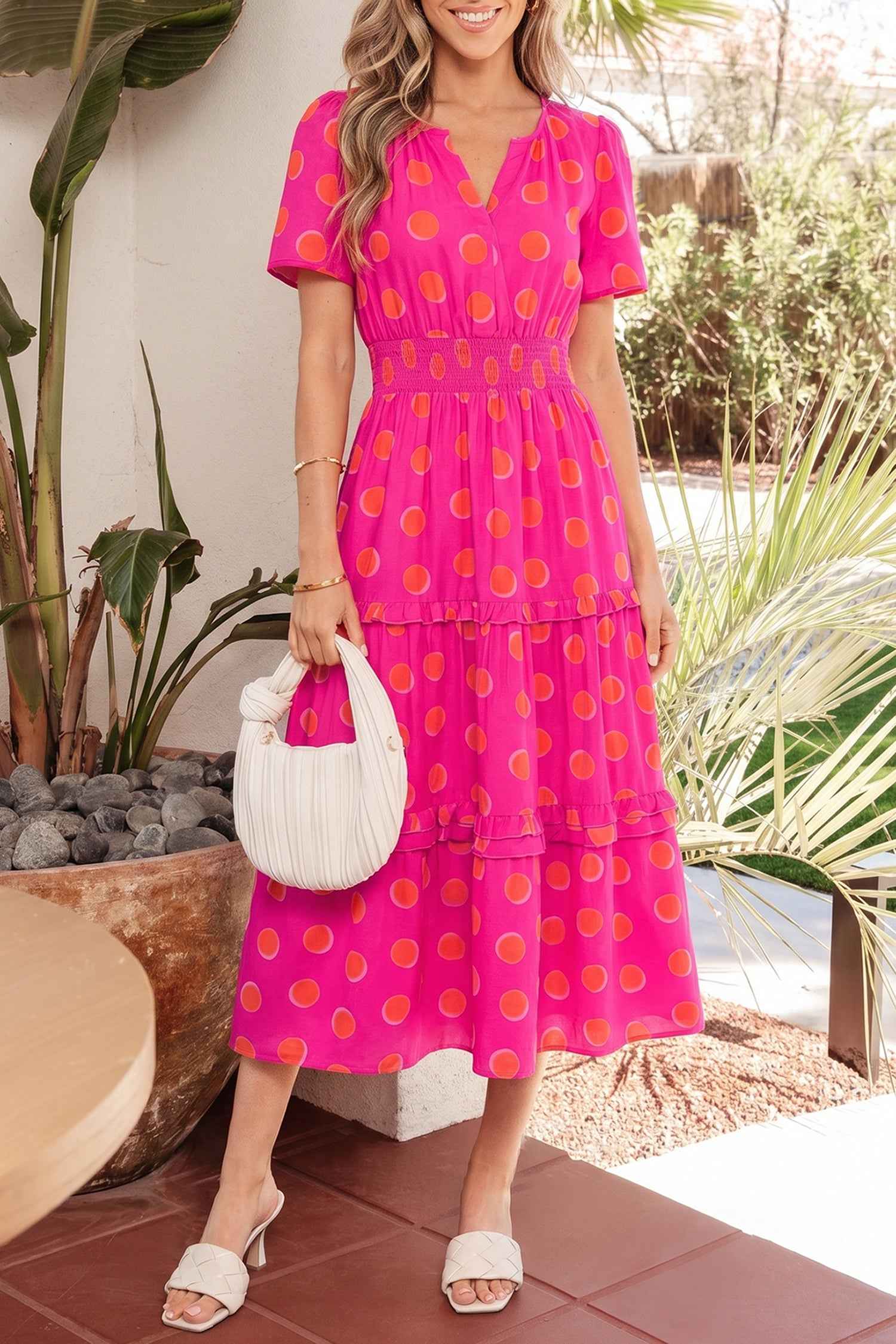 Robe mi-longue rose à pois jaune, encolure V, volants étagés.