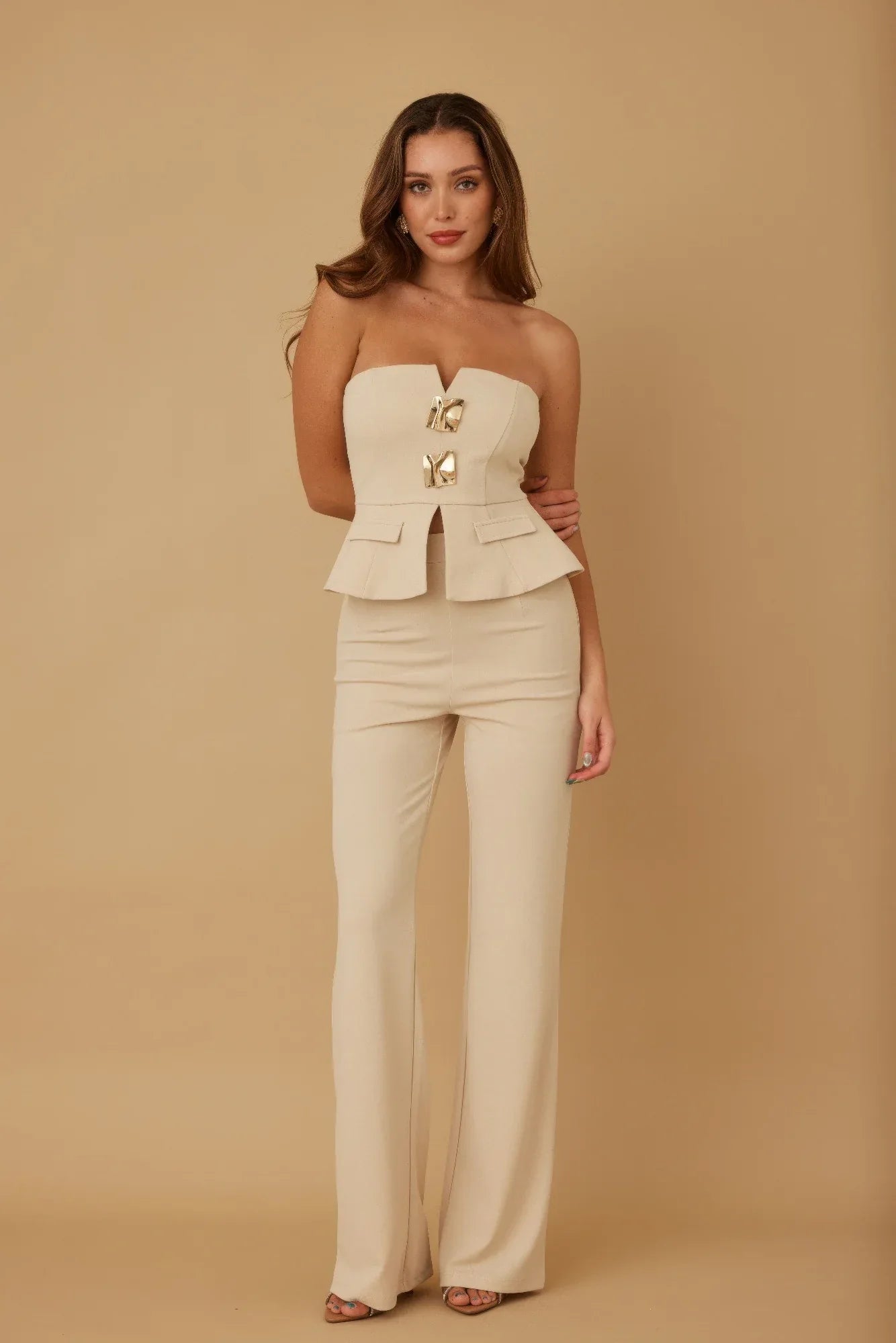 Ensemble deux pièces : bustier blanc froissé et pantalon long, bijoux dorés au buste