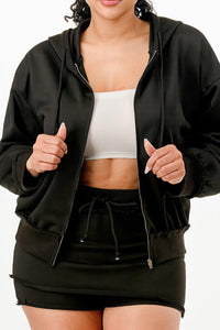 Veste zippée noire à capuche et jupe-short noire, fermeture éclair visible