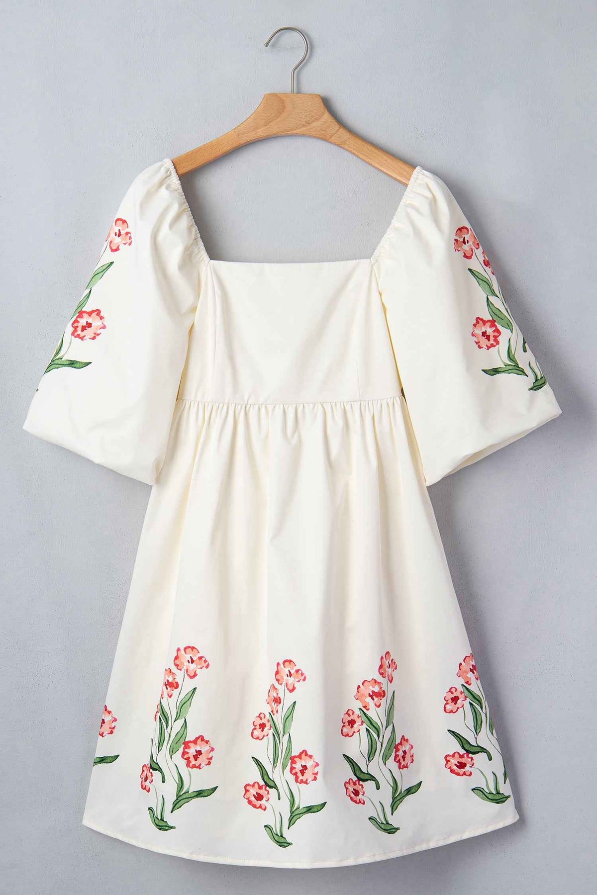Robe babydoll crème imprimée de fleurs rouges, encolure carrée et manches bouffantes.