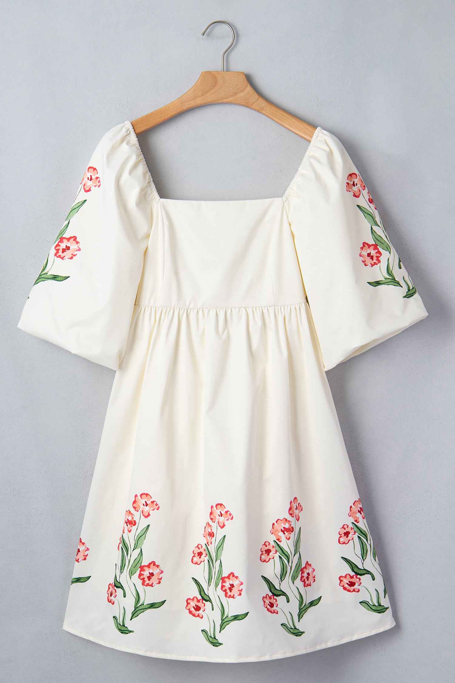 Robe babydoll crème imprimée de fleurs rouges, encolure carrée et manches bouffantes.