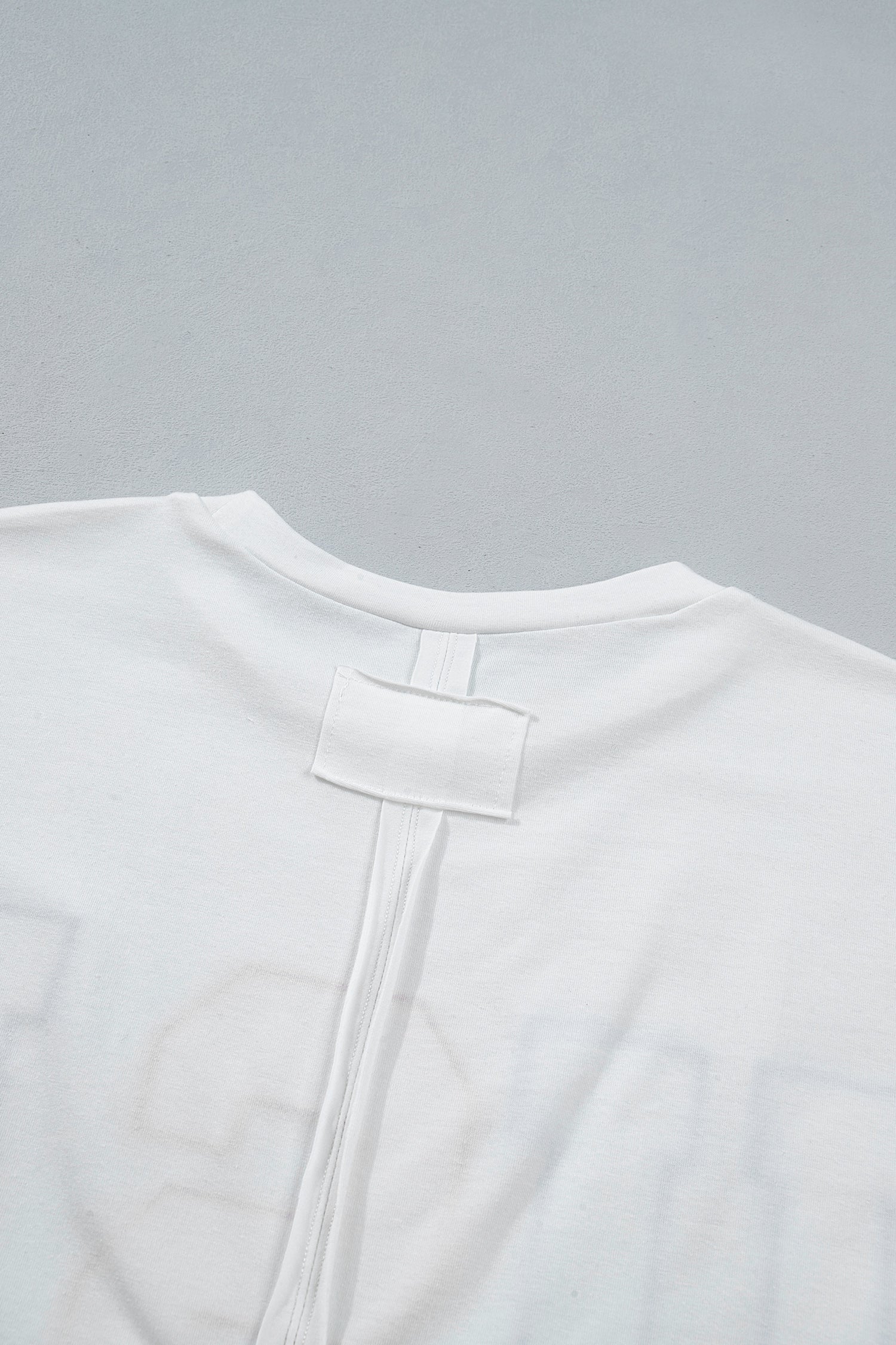 Encolure ronde du t-shirt blanc, étiquette et couture dans le haut du dos.