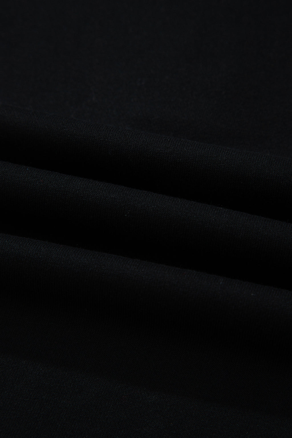 Haut polo bicolore en denim, détail du tissu noir avec plis légers.