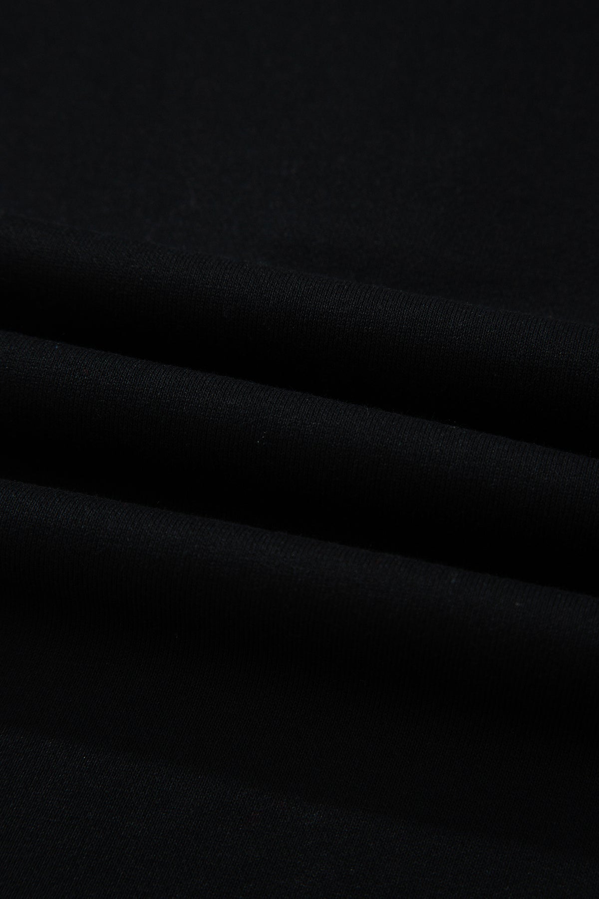 Haut polo bicolore en denim, détail du tissu noir avec plis légers.