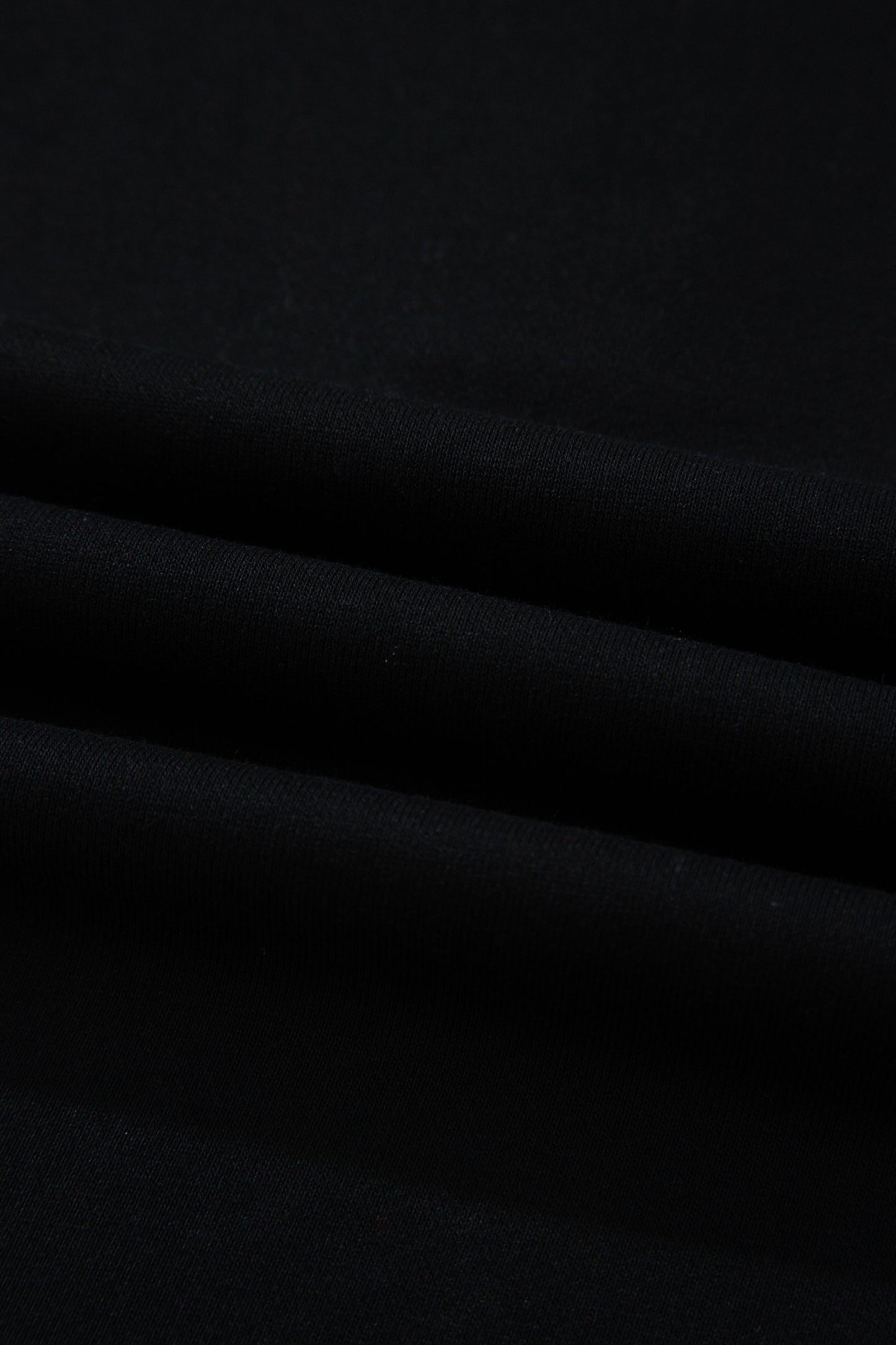 Haut polo bicolore en denim, détail du tissu noir avec plis légers.