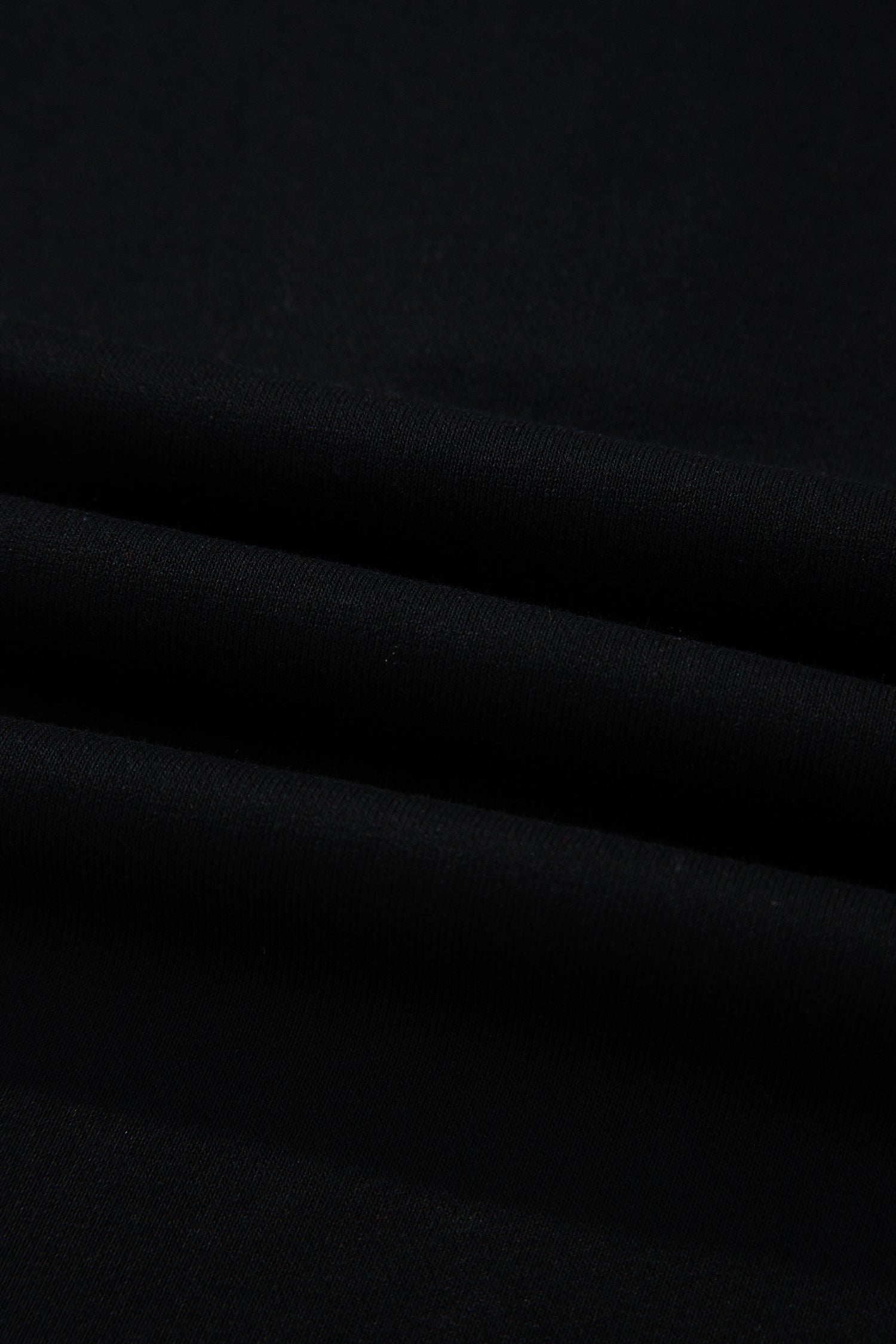 Haut polo bicolore en denim, détail du tissu noir avec plis légers.