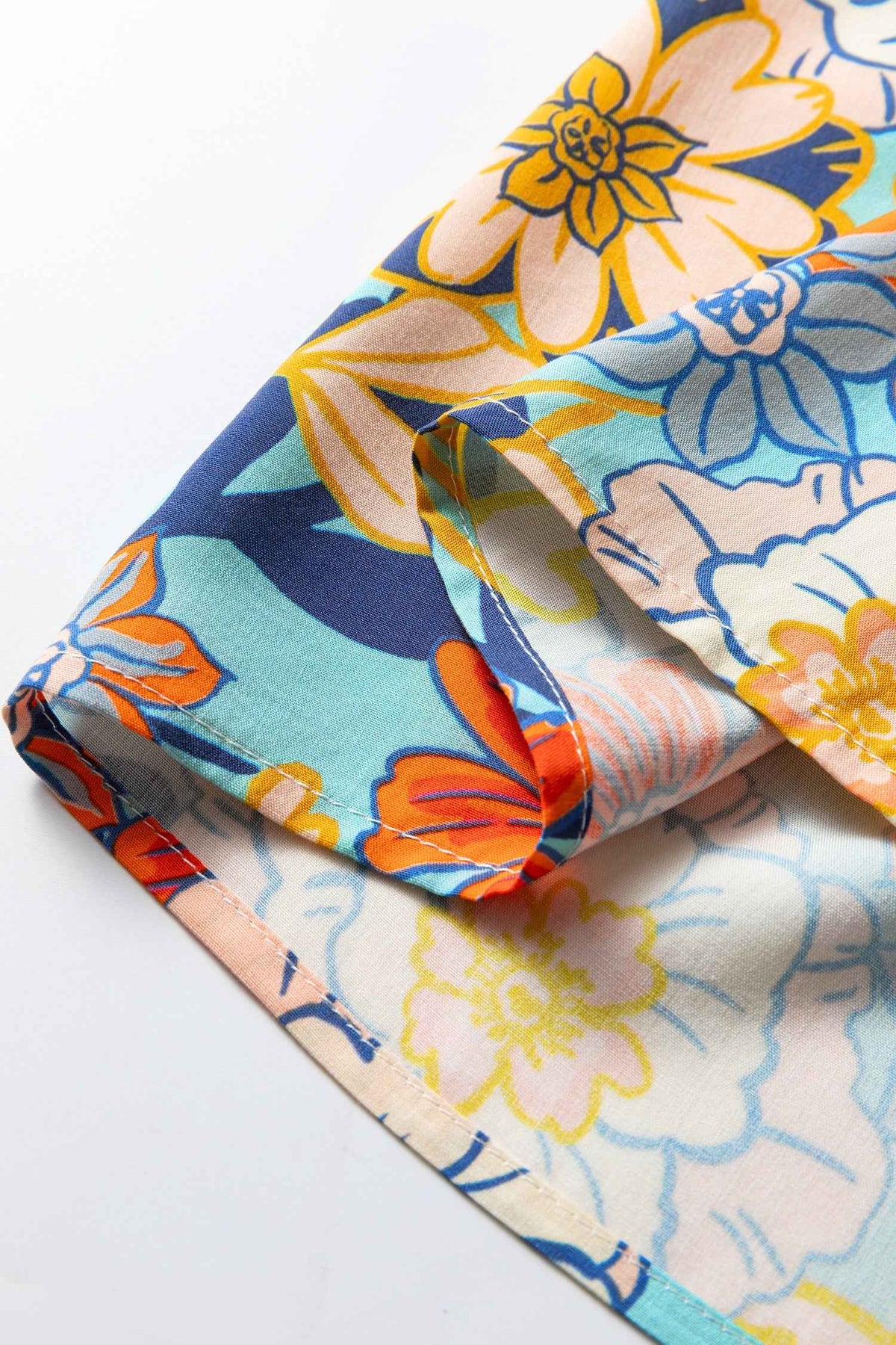 Détail tissu robe : fond bleu clair et grandes fleurs jaunes, oranges et roses