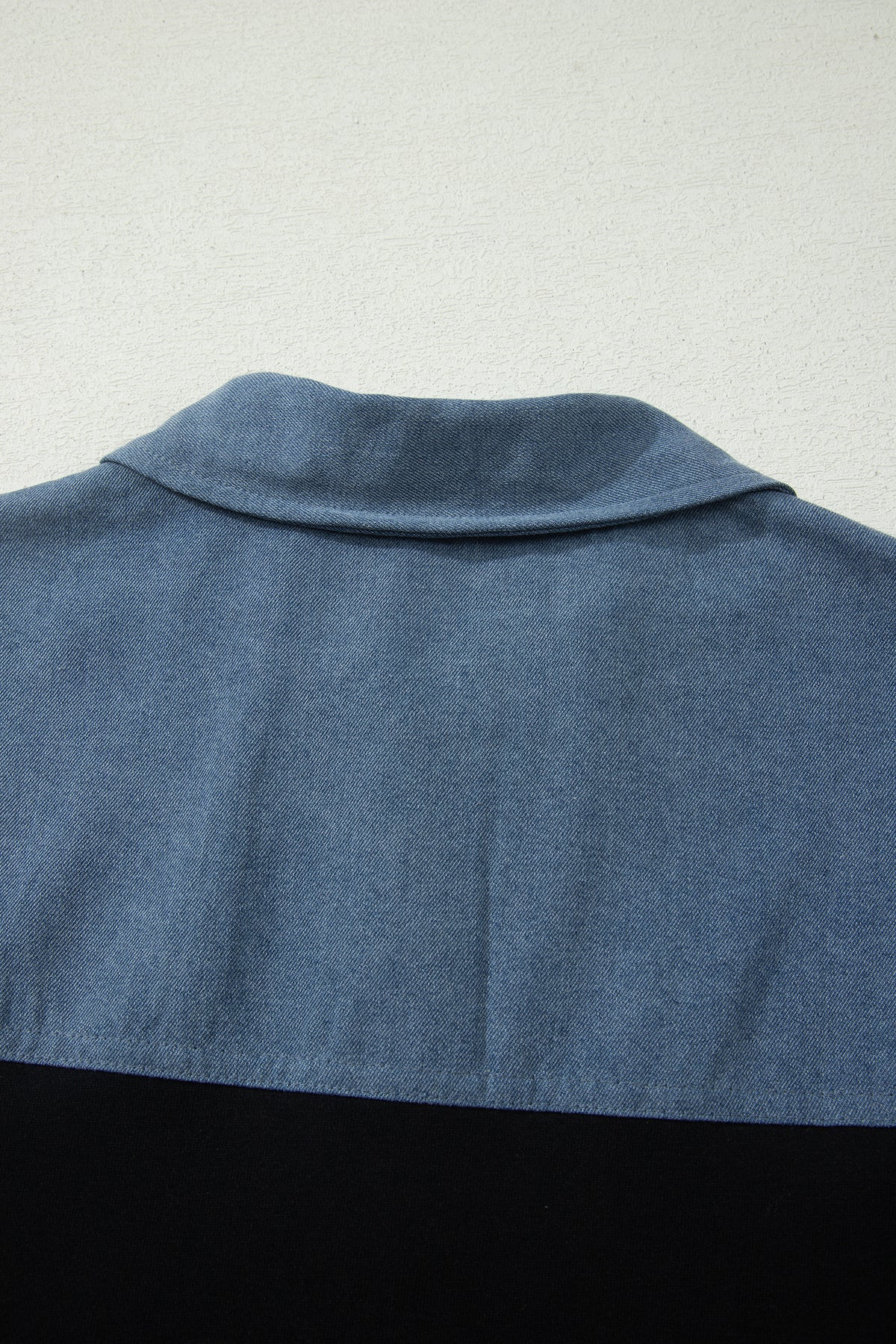 Haut polo bicolore en denim, vue dos : col et haut bleu sur base noire.