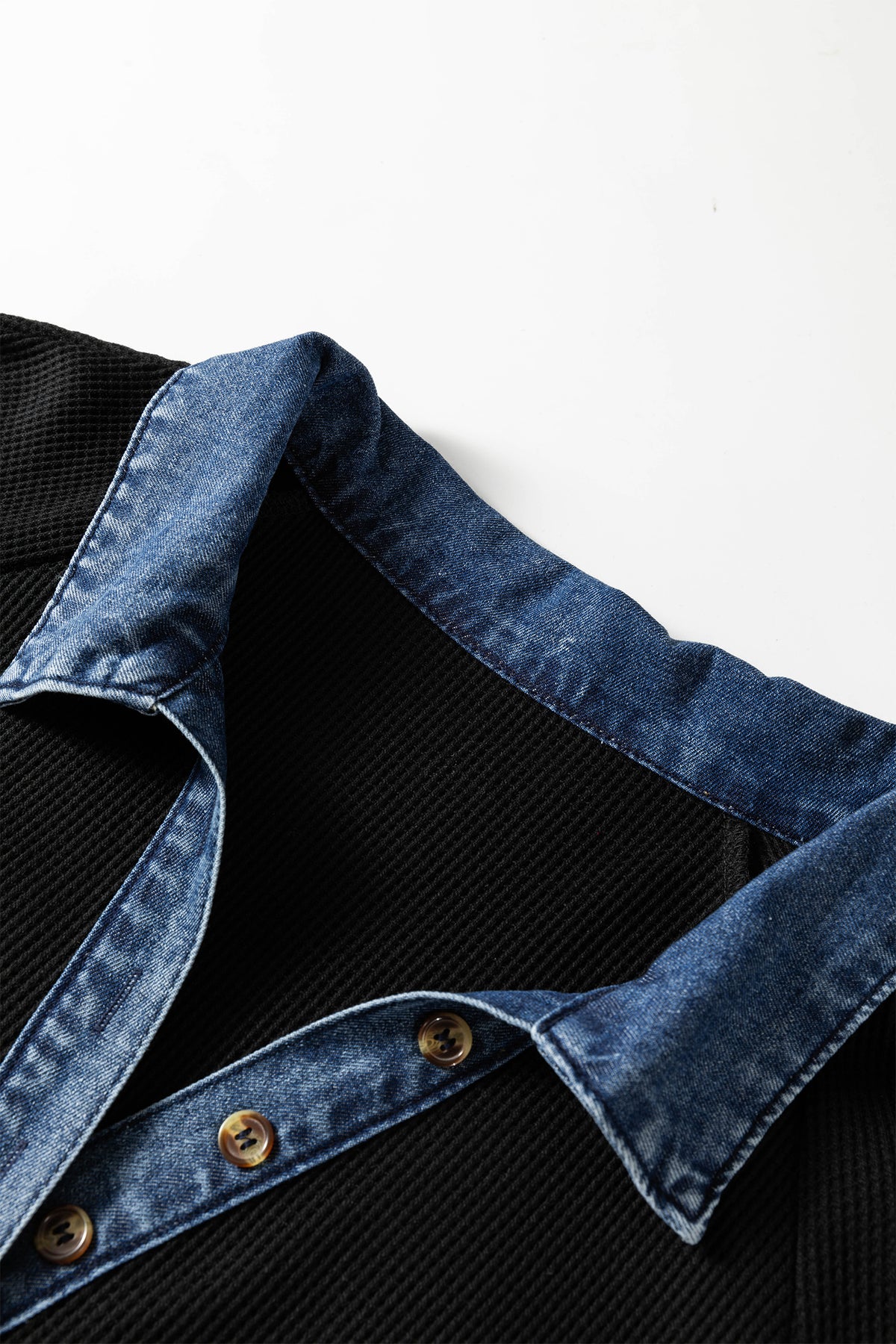 Col en denim bleu avec surpiqûres et boutonnière sur robe noire.