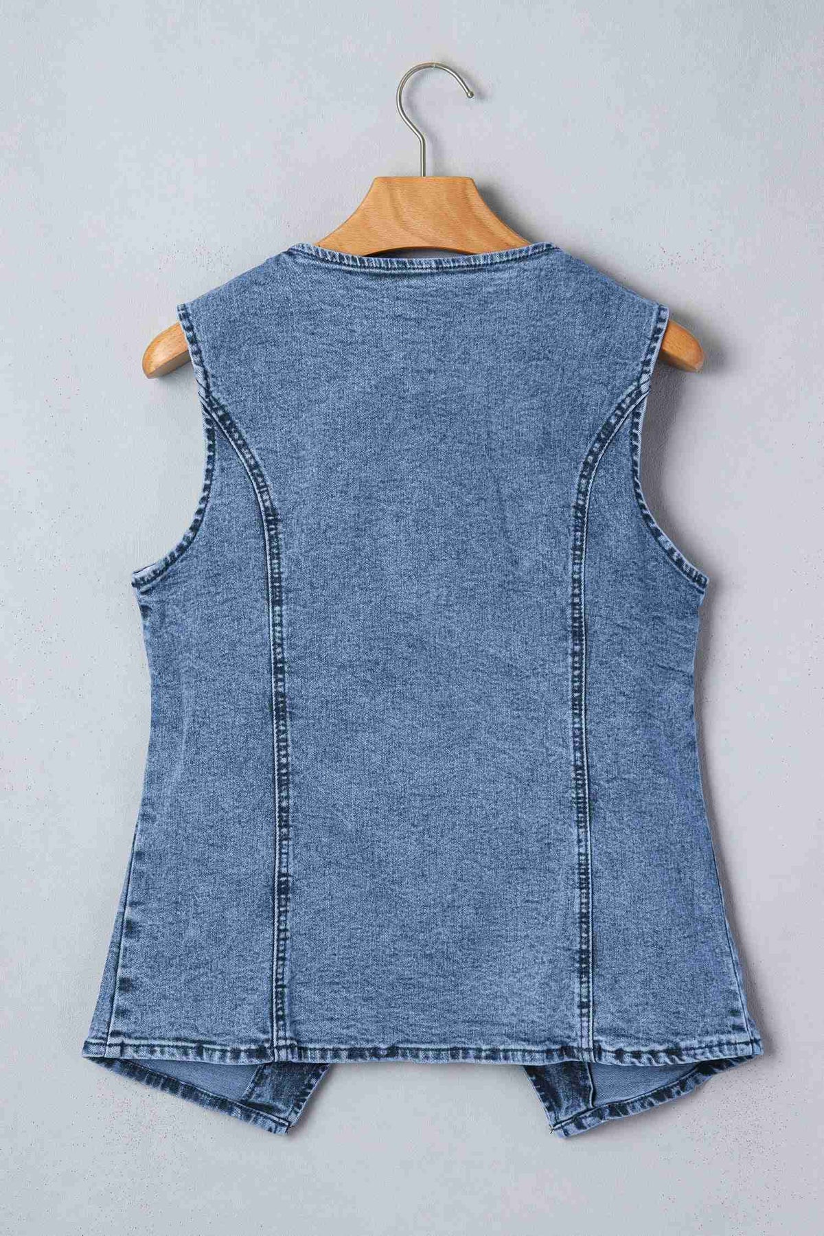 Gilet en denim bleu sans manches, dos uni avec coutures verticales, sur cintre