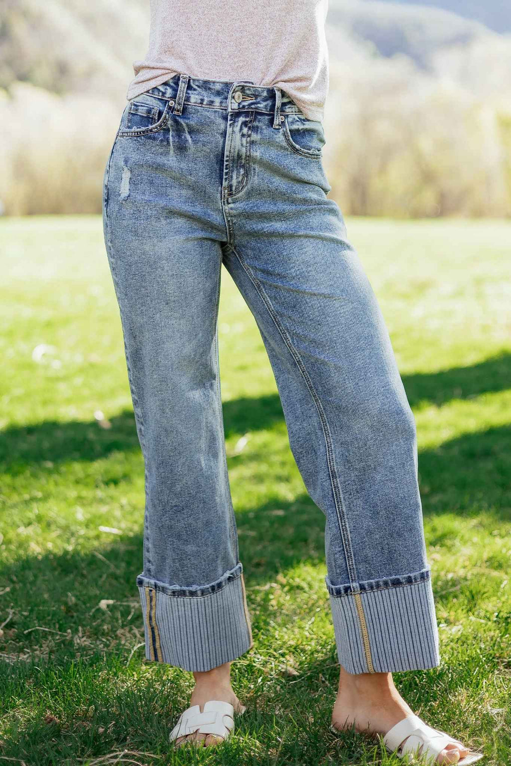 Jean bleu délavé femme avec revers côtelés, coupe ample droite, couture de côté visible.