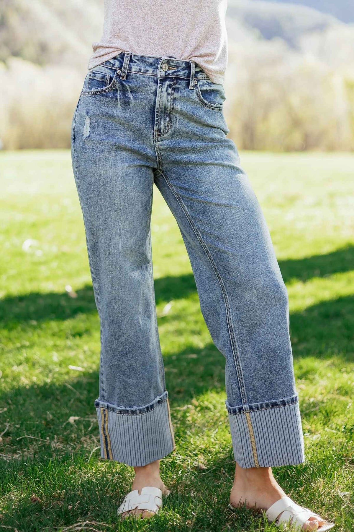 Jean bleu délavé femme avec revers côtelés, coupe ample droite, couture de côté visible.