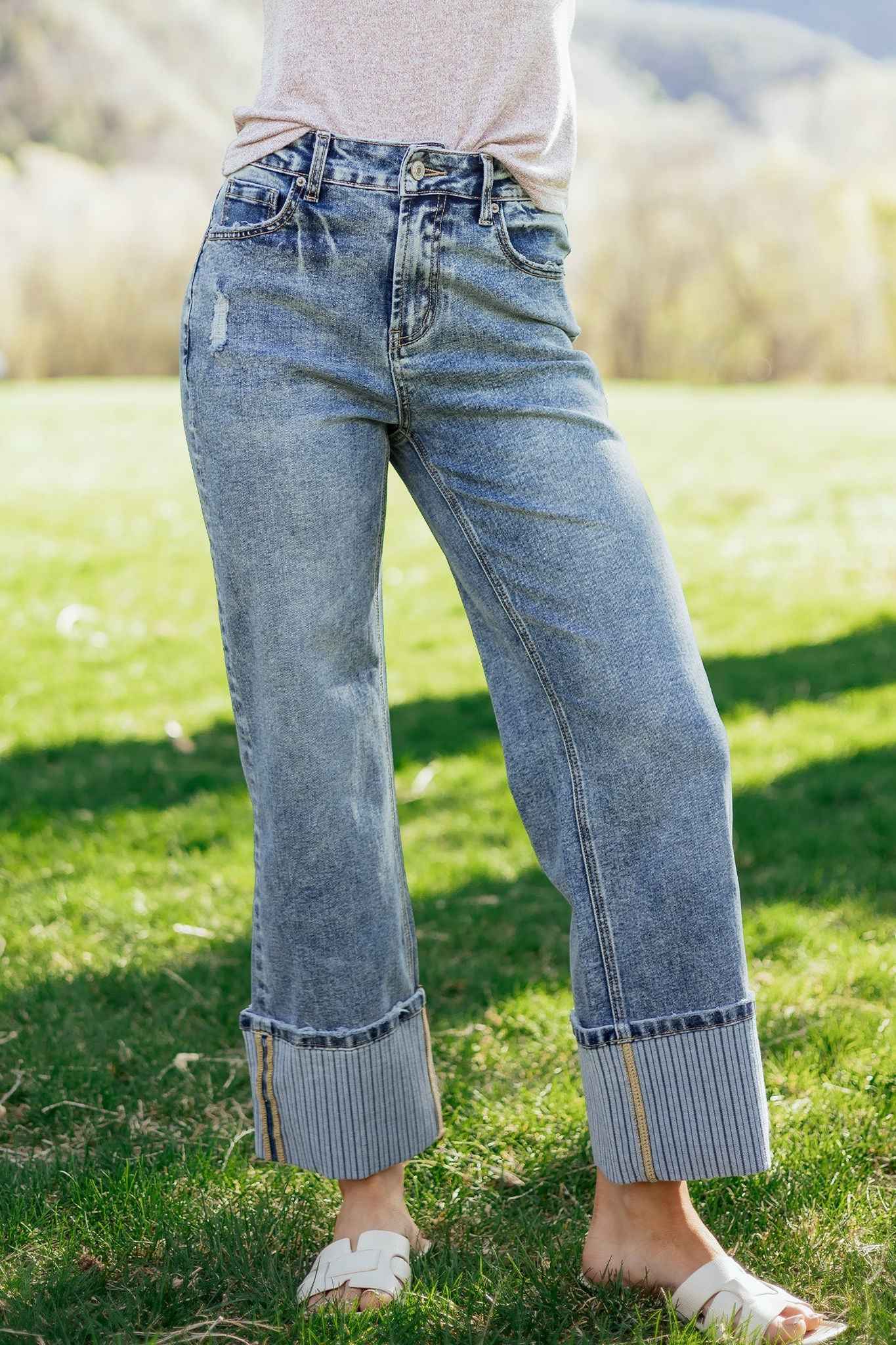 Jean bleu délavé femme avec revers côtelés, coupe ample droite, couture de côté visible.