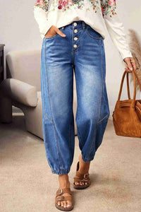 Jean bleu taille haute fuselé, 4 boutons, poches, bas resserré avec couture.