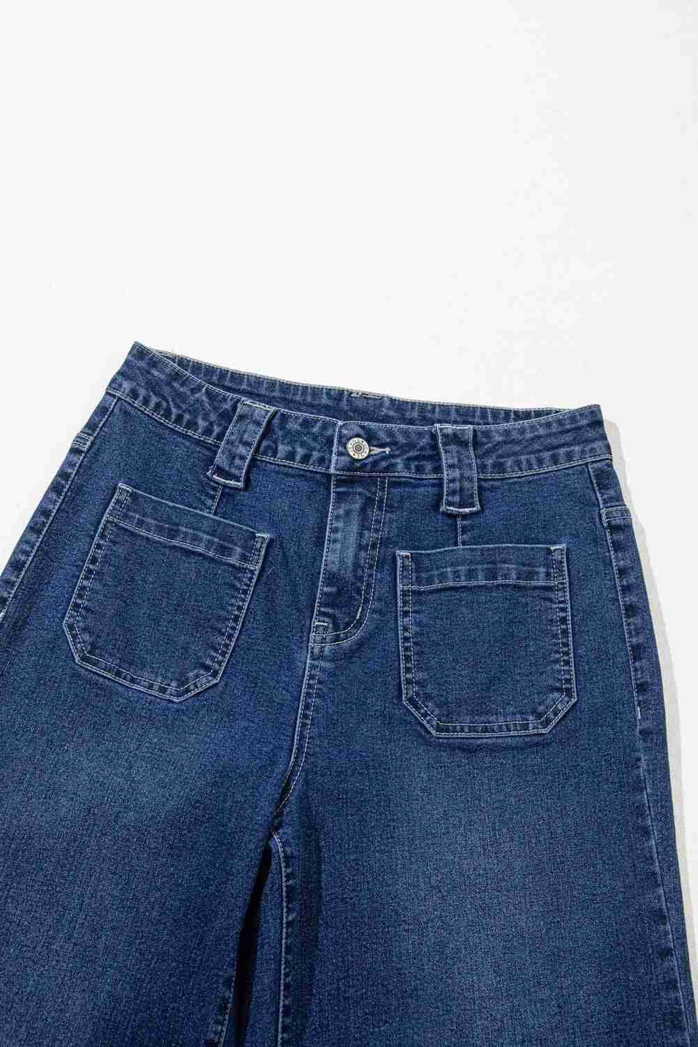 Jean bleu taille haute ample, gros plan poches arrière et ceinture boutonnée.