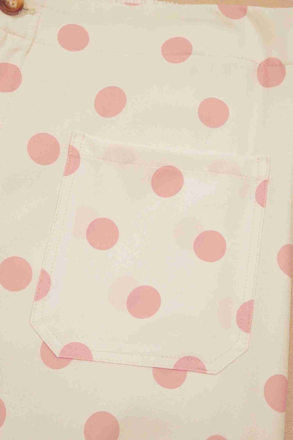 Tissu du pantalon blanc à pois roses, couture et bordure d’ourlet
