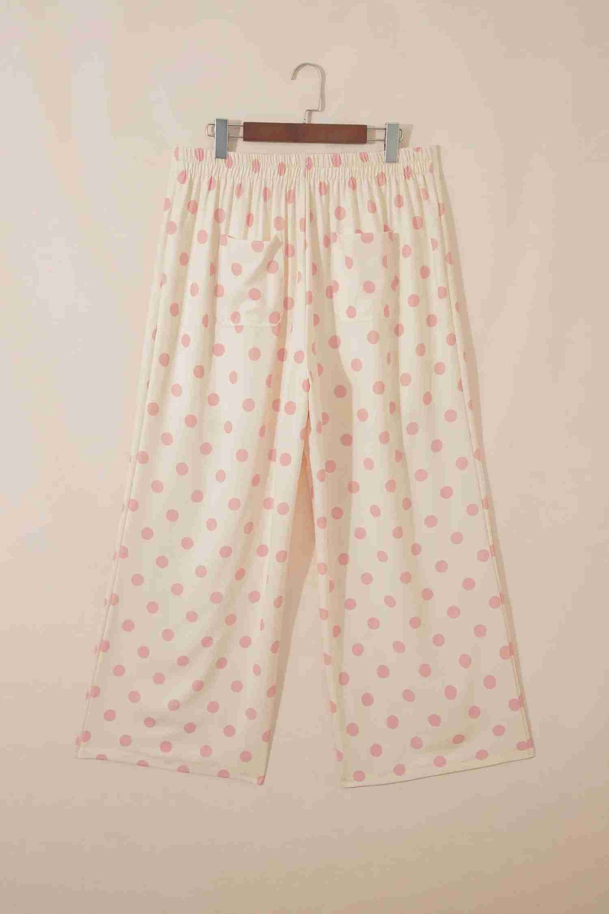 Dos du pantalon blanc à pois roses sur cintre, taille mi-haute