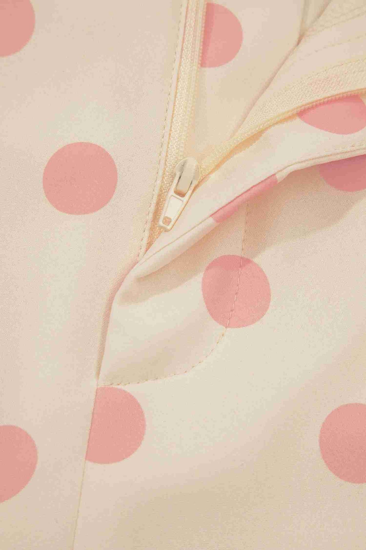 Détail de la fermeture zippée du pantalon blanc à pois roses