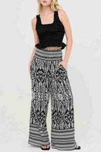 Pantalon long ample noir et blanc à motif fleuri, taille smockée élastique.