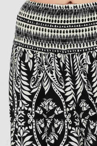Pantalon noir à motif végétal blanc, taille smockée et ourlet à rayures contrastées.