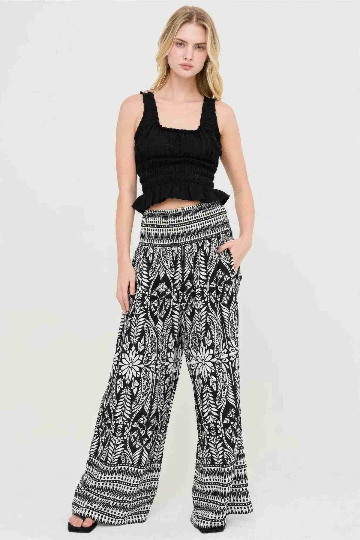 Pantalon fluide noir et blanc à motifs floraux, taille smockée, coupe ample et longue.