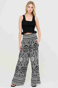 Pantalon fluide noir et blanc à motifs floraux, taille smockée, coupe ample et longue.
