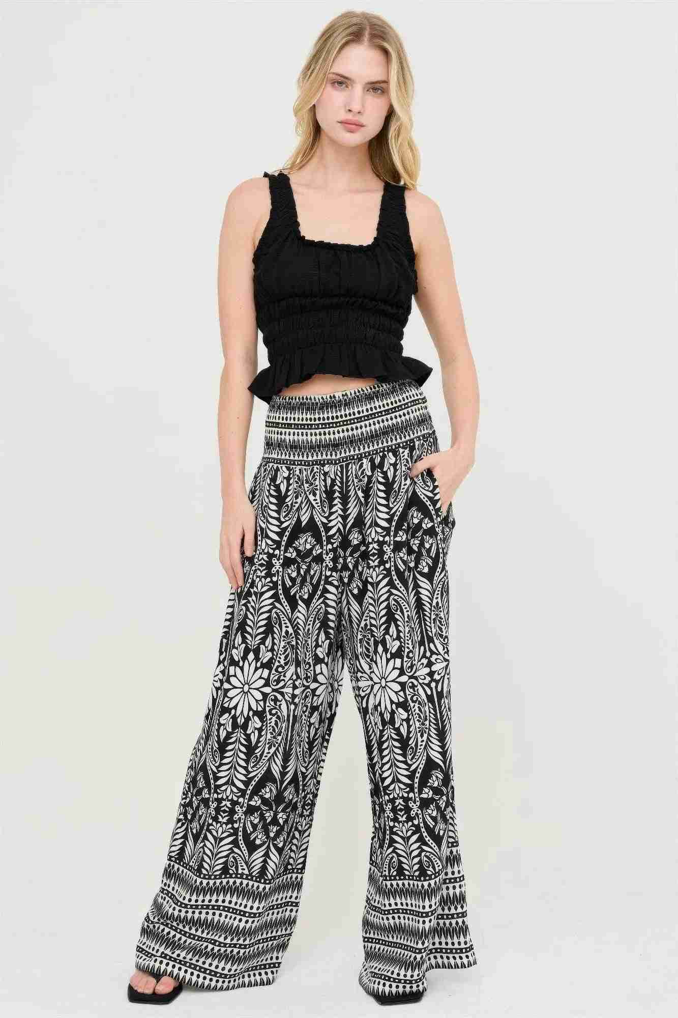 Pantalon fluide noir et blanc à motifs floraux, taille smockée, coupe ample et longue.