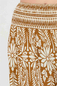 Pantalon ocre à motif floral blanc, détail du tissu avec imprimé décoratif.