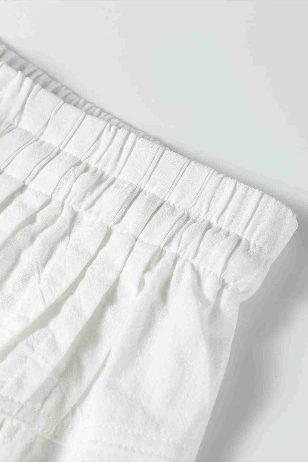 Ceinture élastique du pantalon large écru avec plis et boutonnage décoratif